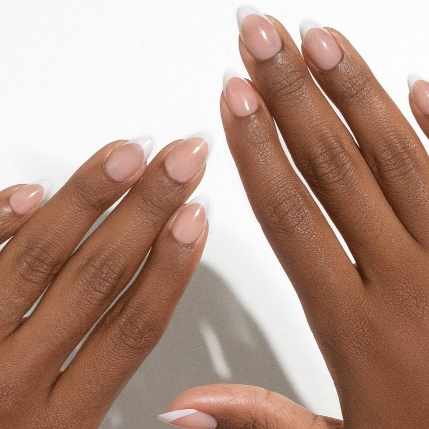 Two hands with light pink nail polish on a neutral background