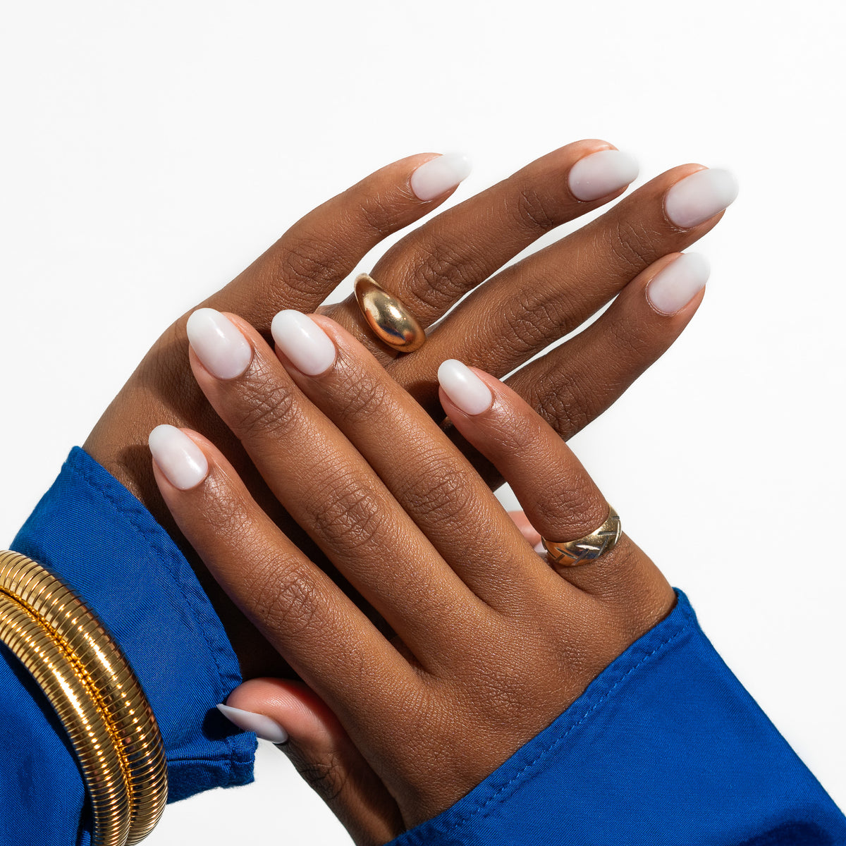 A set of creamy white press-on nails presented in an oval shape, designed to fit naturally into the nail bed. The image shows the nails on a person's hands, indicating the fit and elegance of the product.