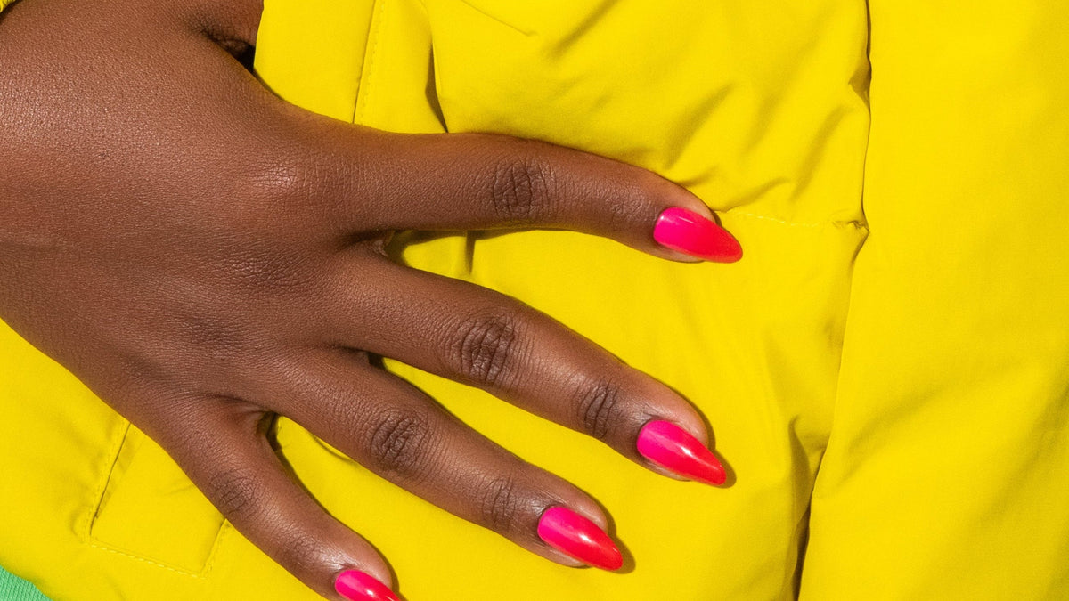 Close-up of a person wearing a bright yellow jacket with pink nail polish.