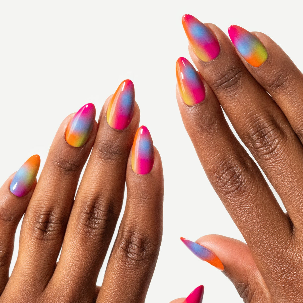 Two hands with multicolored nail polish on a light gray background