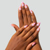 Two hands with pink nail polish on a light gray background