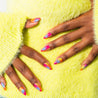 A set of press-on nails featuring a gradient of warm colors, resembling a tropical sunset, on a person's hands.