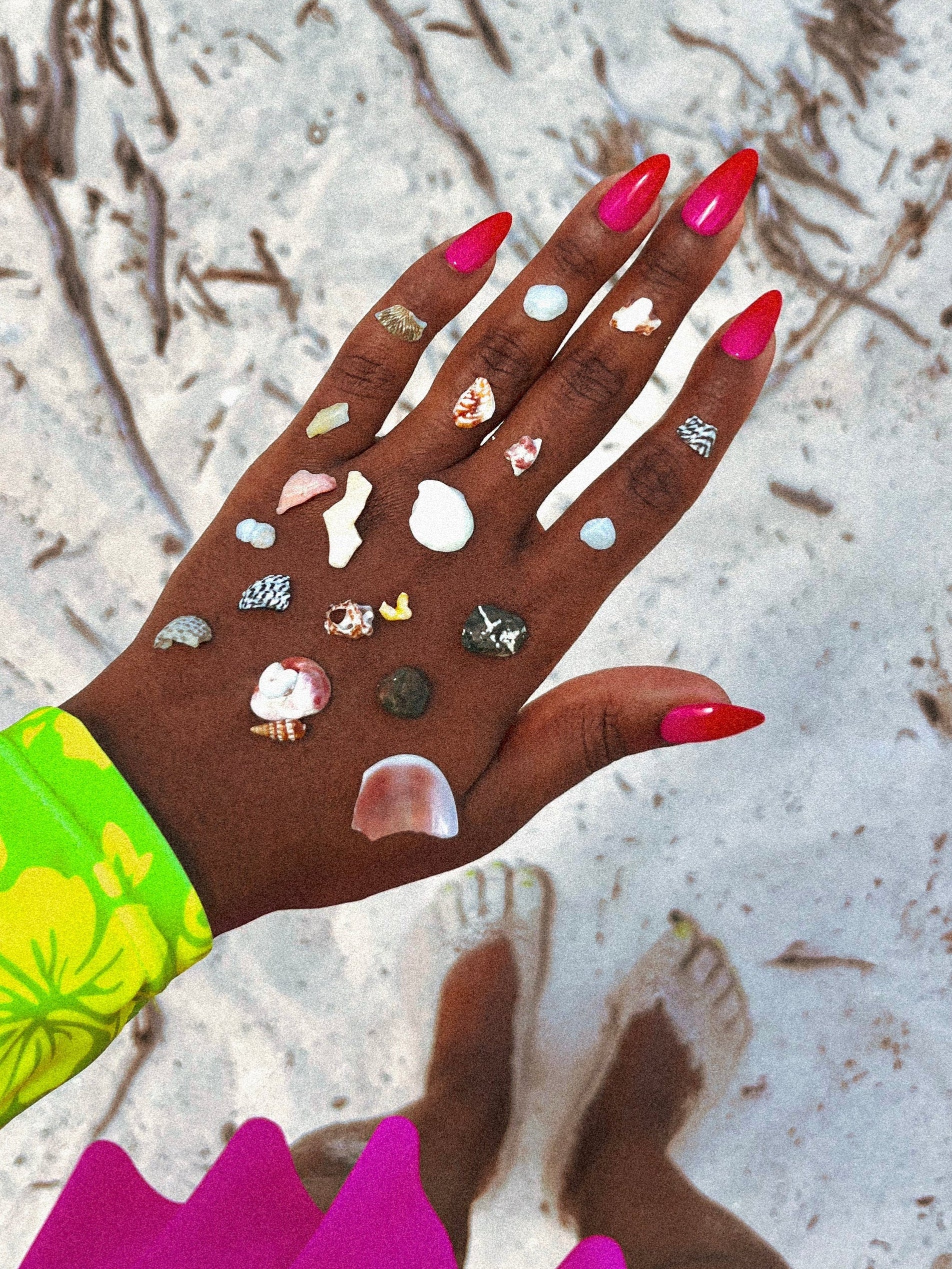 Hand with colorful nail polish and decorative elements against a sandy background press on nails